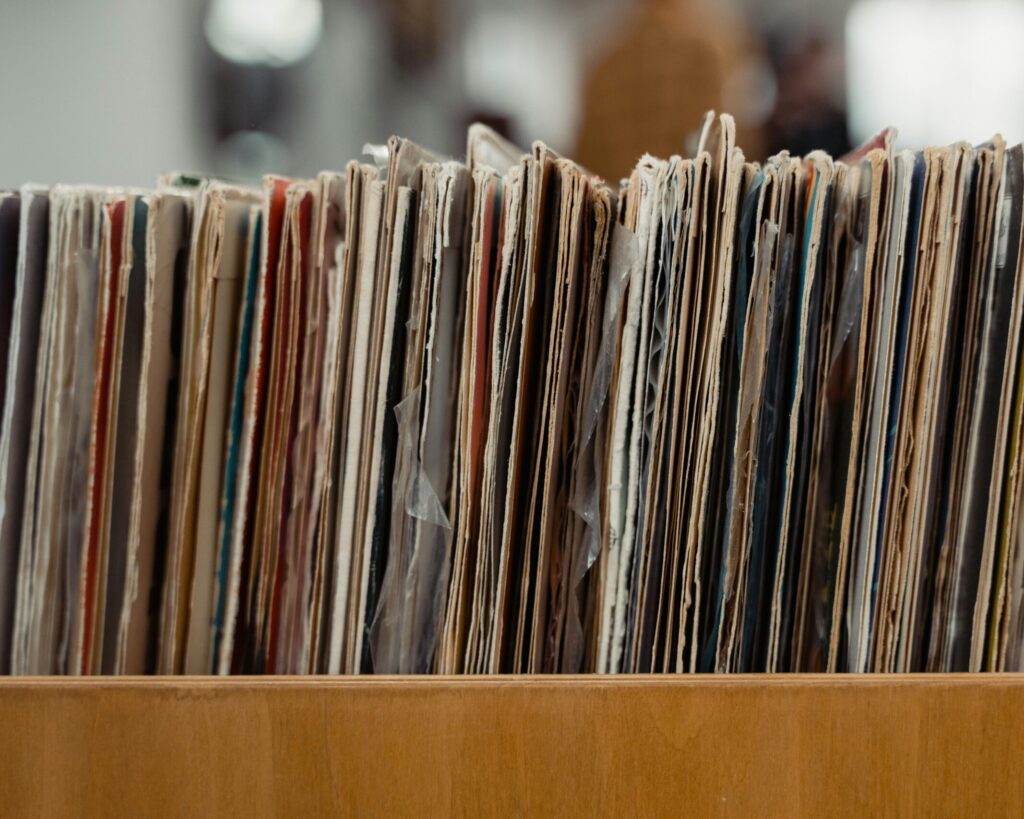 Stack of vintage vinyl records stored in a wooden crate, showcasing a retro vibe.